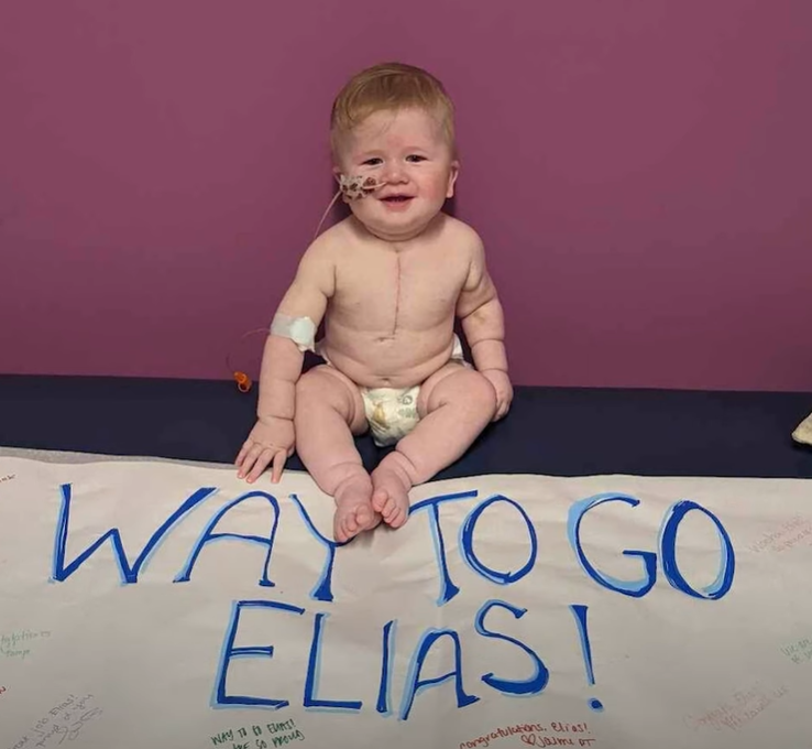 baby Elias sitting on a banner that says "Way to go Elias"