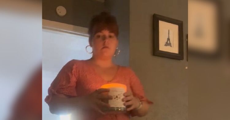 Image shows a woman carrying a lit candle from one room to another.