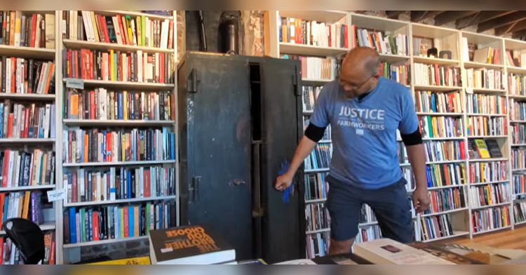 Bookstore worker standing in front of an unopened safe, about to reveal the contents.