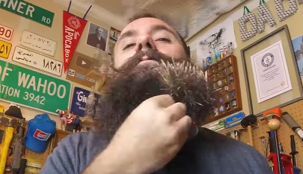 Image shows the world record holder placing toothpicks in his beard to break the record.