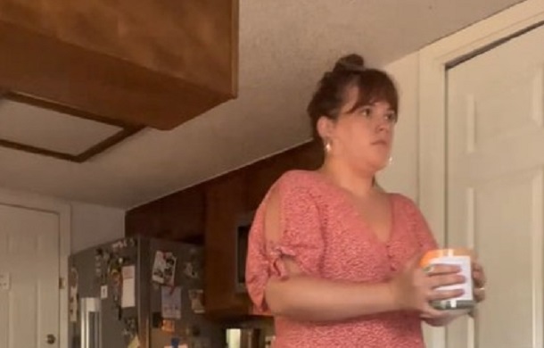 Image shows a female performing a ritual out of habit, carrying a lit candle from one location to another.