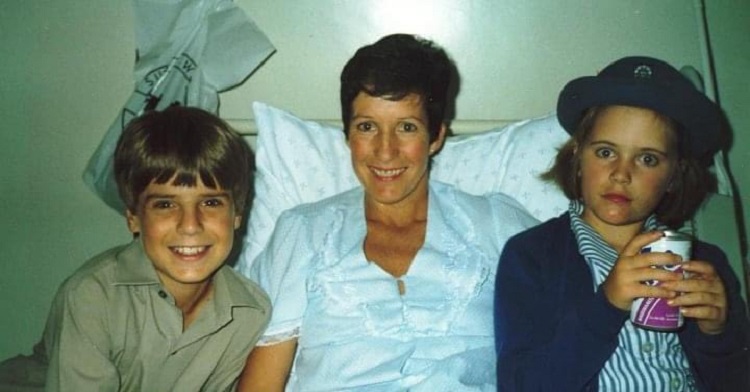 Image shows adoptive mom in a hospital bed with her two children sitting on either side of her.