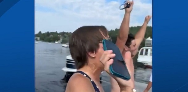 Celebrations after a phone rescue from 15 feet of water. Image shows a swimmer with arms raised and the phone owner holding the still-working phone aloft.