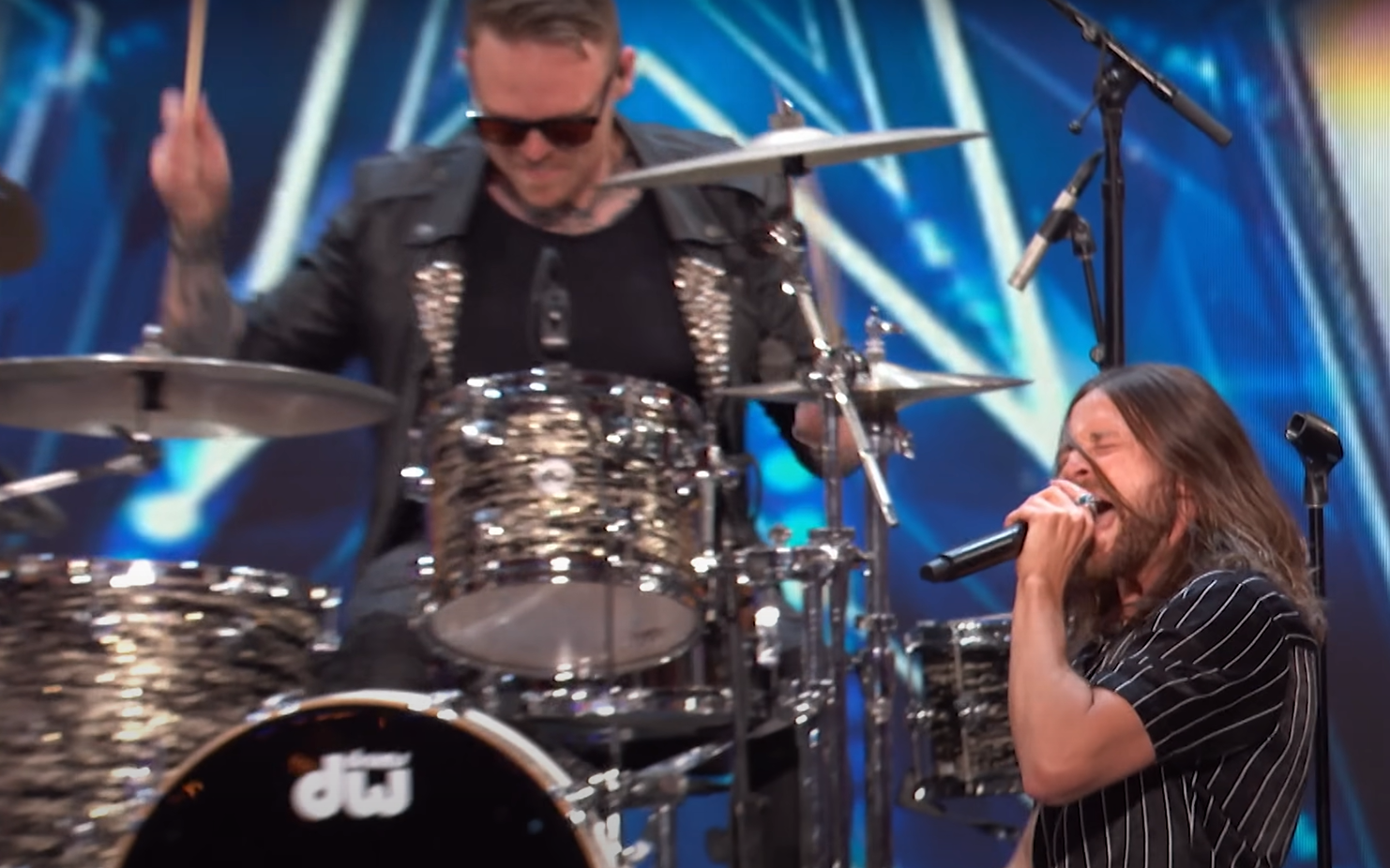 True Villains' vocalist singing and drummer playing in the background, performing