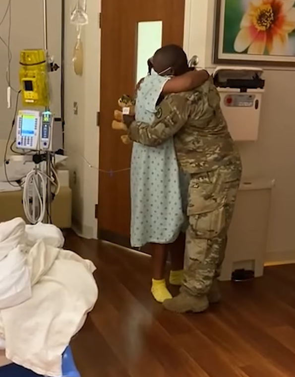 Army husband hugs pregnant wife in the hospital.
