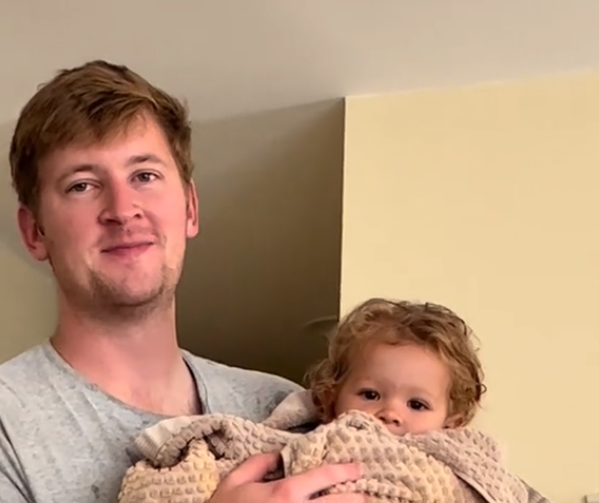 Father-daughter moment has dad smiling and baby daughter looking at the camera.
