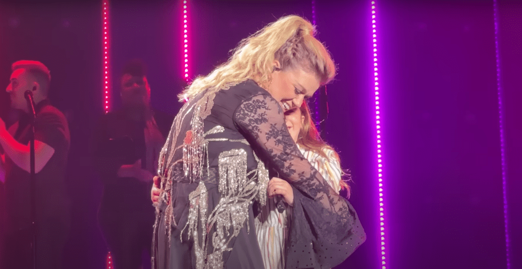 Kelly Clarkson and daughter hug on stage.