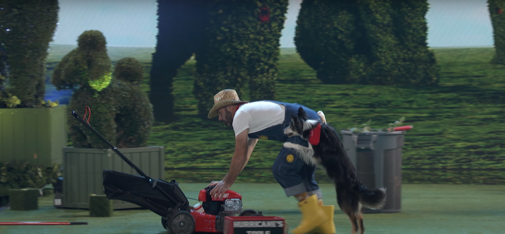 Dog and trainer duo push a lawn mower together.