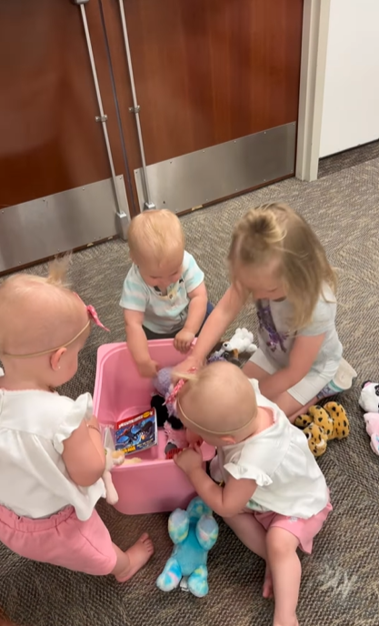 Torrey's four kids are gathered around a small pink container with toys and are going through them.