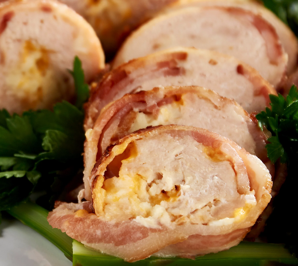 Close up of a Colossal Bacon Wrapped Stuffed Chicken from Family Farms. It's been cut so the inside can be viewed.