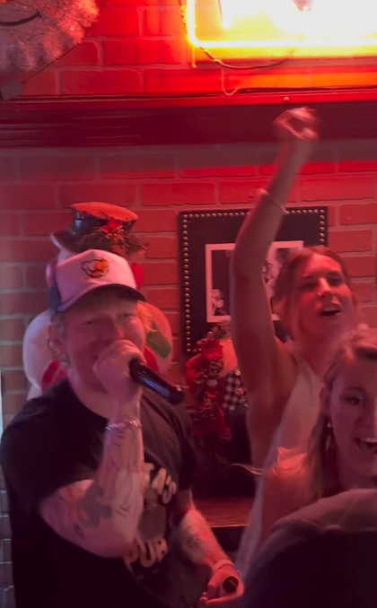 Ed Sheeran sourit en chantant dans un micro au Santa's Pun à Nashville, Tennessee.