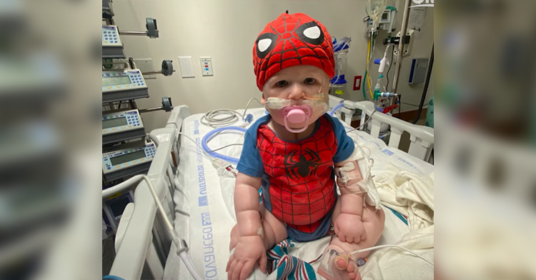 baby elias in a spider-man costume, sitting in a hospital