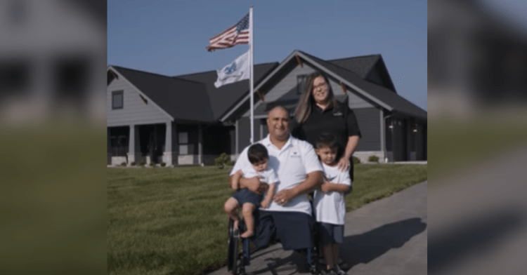 family stands in front of house with American flag.