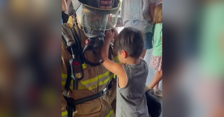 Firemand helps blind child "see" his uniform.