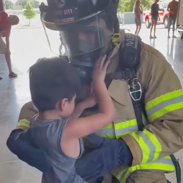 Fireman holds young boy in his arms.