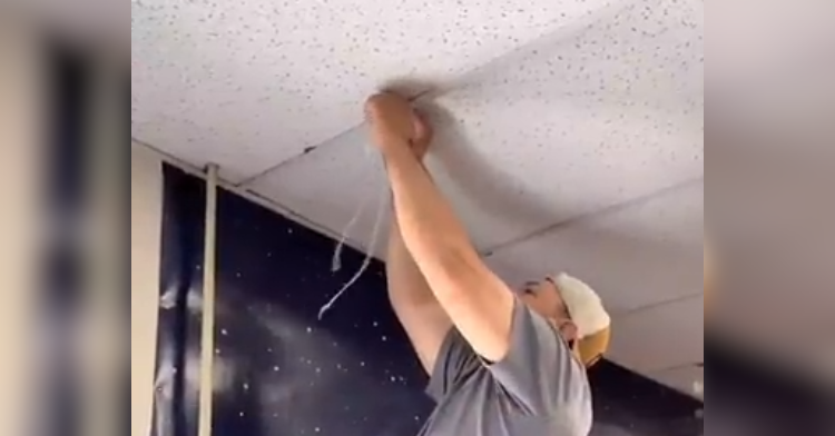 man hangs something from ceiling