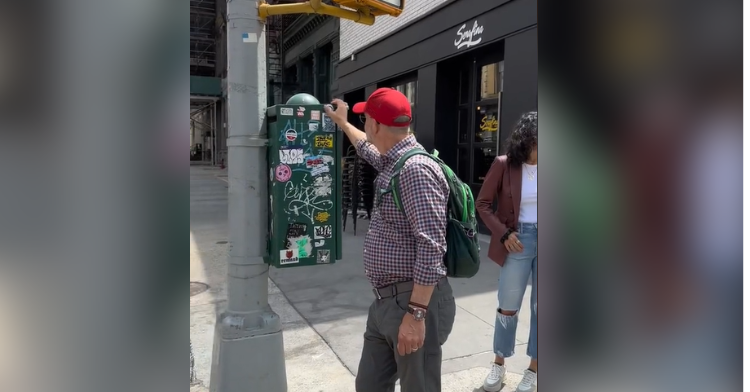 man in red cap puts stickers on stoplight