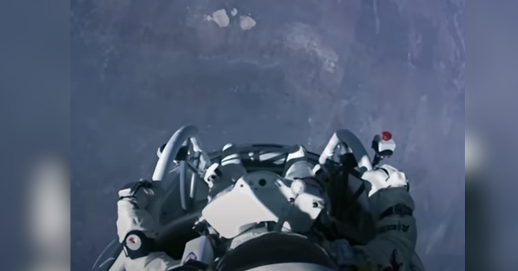 man in space suit looks down at earth