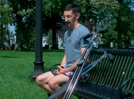man sits on park bench with pogo stick