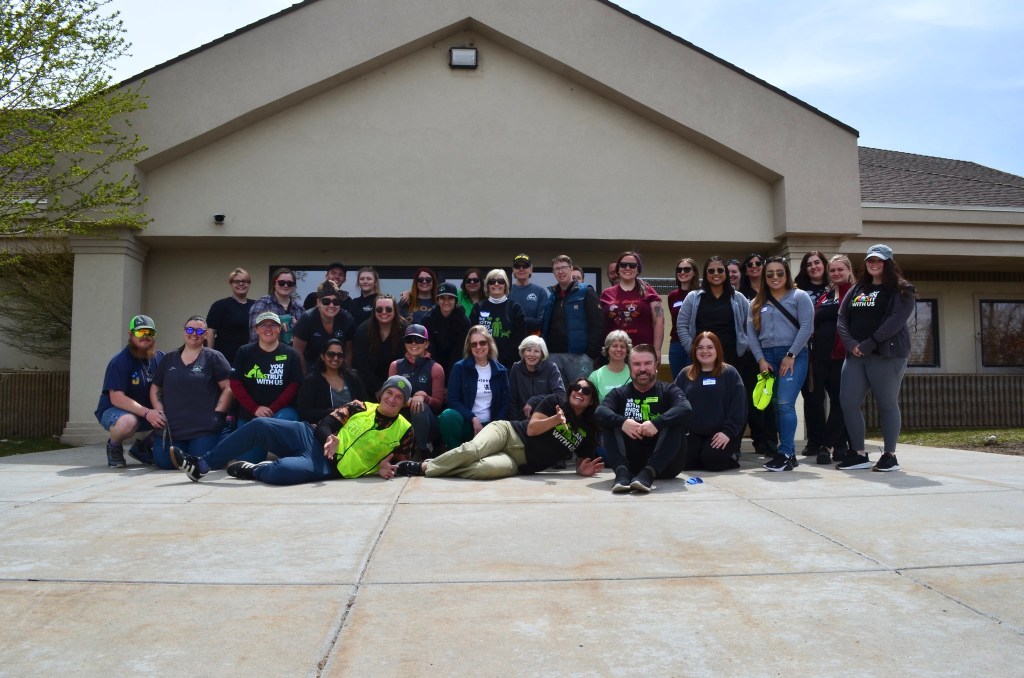 A group of people who appear to be workers and volunteers for Ruff Haven pose outside a building for a group photo.