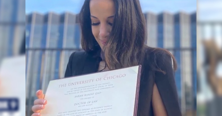 Sarah Gad smiles softly as she looks down at her diploma for her law degree.