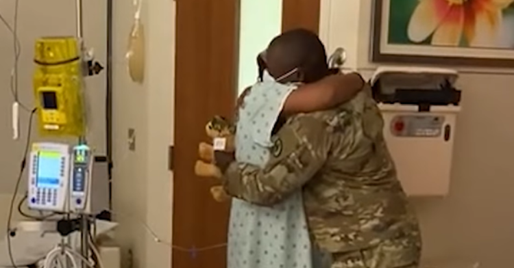 Soldier hugs pregnant wife in the hospital.