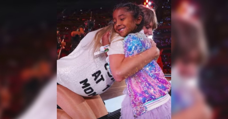Taylor Swift closes her eyes as she hugs 6-year-old Bianka Bryant during her performance of "22" at the Eras Tour in Los Angeles.
