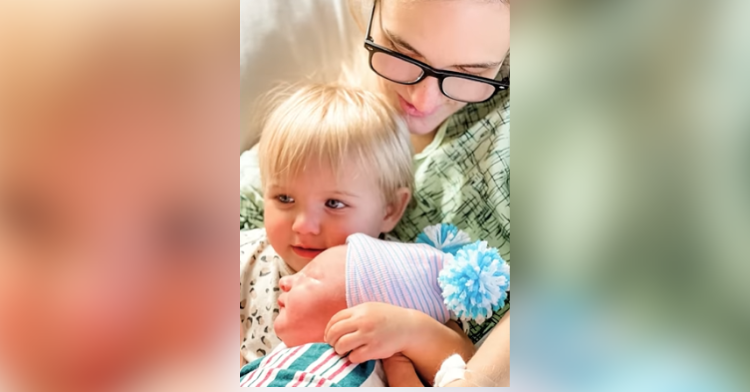 toddler holding new sibling in hospital