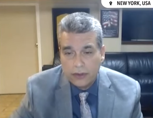 Janitor William Rodriguez talks via video call in an interview. He's wearing a suit and tie.