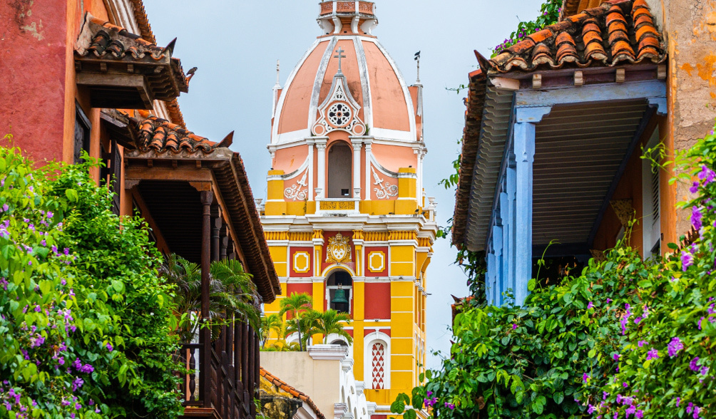 View of colorful buildings with lush greenery adorning the outside of homes.