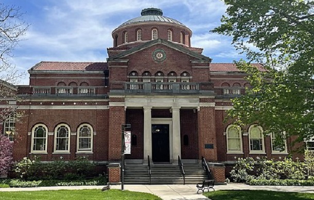 Images shows a front view of Alumni Hall on the campus of Miami Universtity in Oxford, Ohio. The building is a brick, 2-story structure with a set of white columns at the entryway.