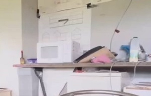 Image shows an office breakroom, focusing on the white microwave on a counter. The area is about to become the scene of a workplace prank.