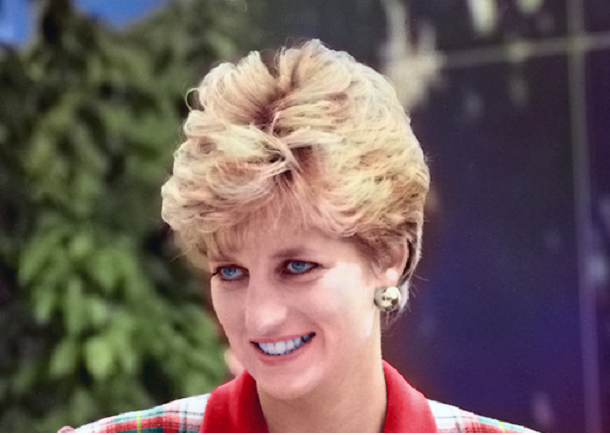 Image shows a head shot of a smiling Princess Diana wearing a red and white plain suit.