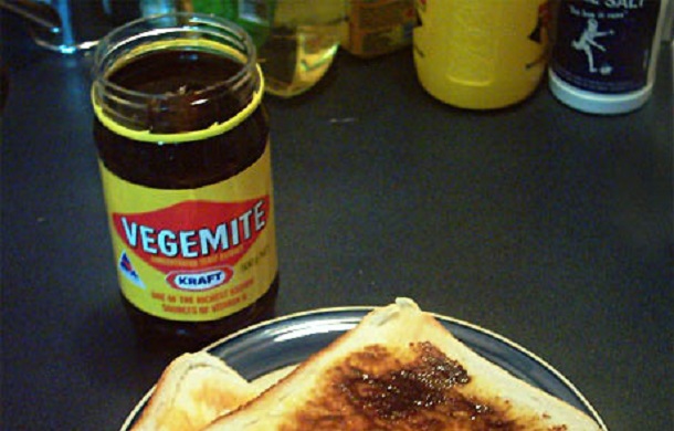 Image shows a jar of Vegemite next to a plate with two pieces of toast. Vegemite is one of the staple foods in Australia.
