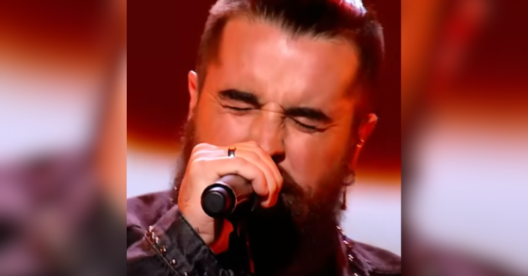 bearded man sings into microphone