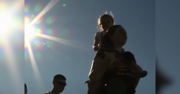 child sits on adult's shoulders