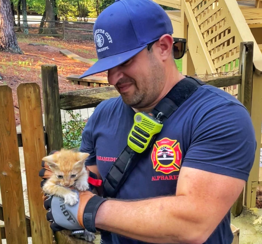 firefighter holding small orange kitten