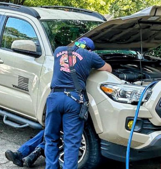 firefighter leaning over truck engine compartment