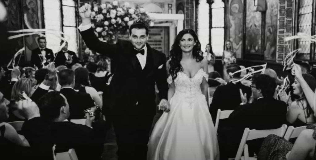Zachary Lazev and his wife walked down the aisle after getting married. They're both smiling and Zachary has a fist raised in the air in celebration.