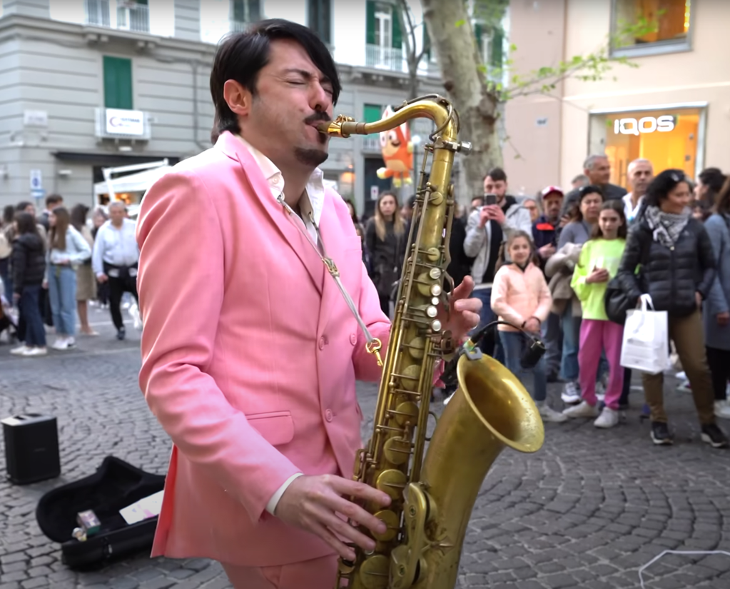 Man in pink suit plays the saxophone.