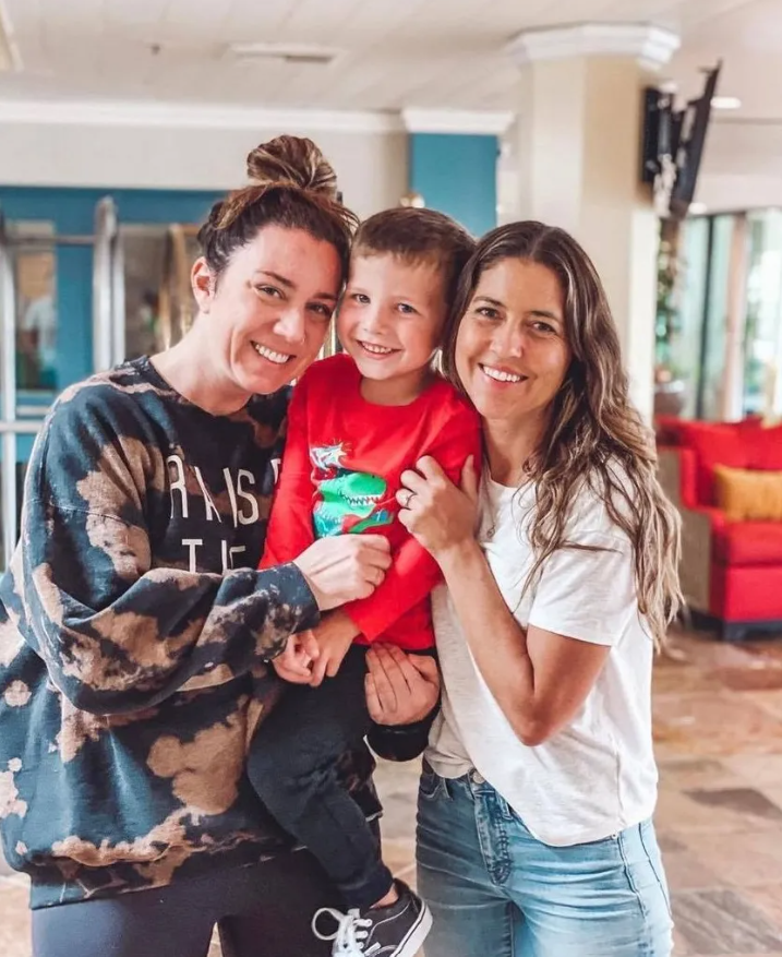 Julia Bonin and Amanda Leigh Ennis smile as they hold Amanda's toddler.
