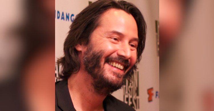 Close up of Keanu Reeves smiling wide.