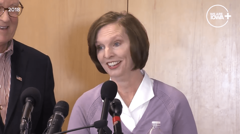 Leryanne West smiles as she talks into a mic at a press conference after winning the lottery.