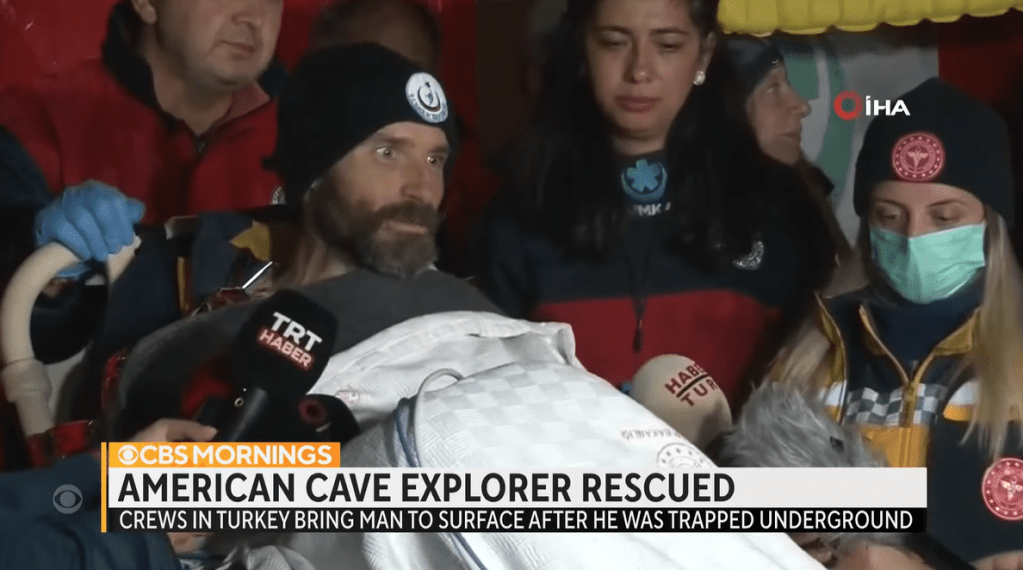 Mark Dickey smiles as he sits in a stretcher. He is talking to the media after being rescued from Morca Cave.