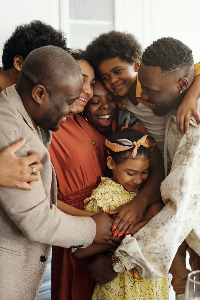 A family of seven have a group hug, smiling.