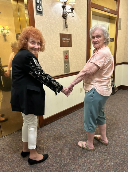 Barbara Carolan and Shirley smiling and holding hands as they wait for an elevator the day they reunited in 2023.