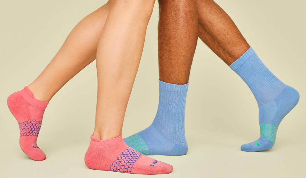 Image shows a pair of male and pair of female legs wearing Bombas socks.