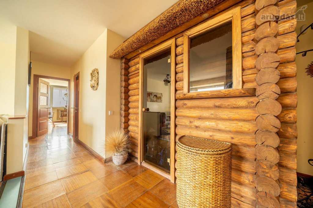 A small, wooden building within a home. It has a glass door, window, and partial roof that leads to the ceiling. It appears to be a sauna.
