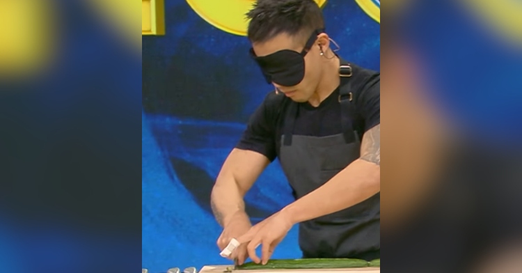 A blindfolded man slices cucumbers.