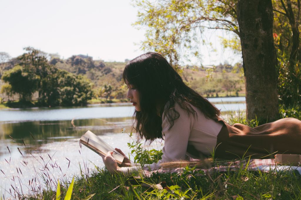 A woman reads words of wisdom under a shady tree.